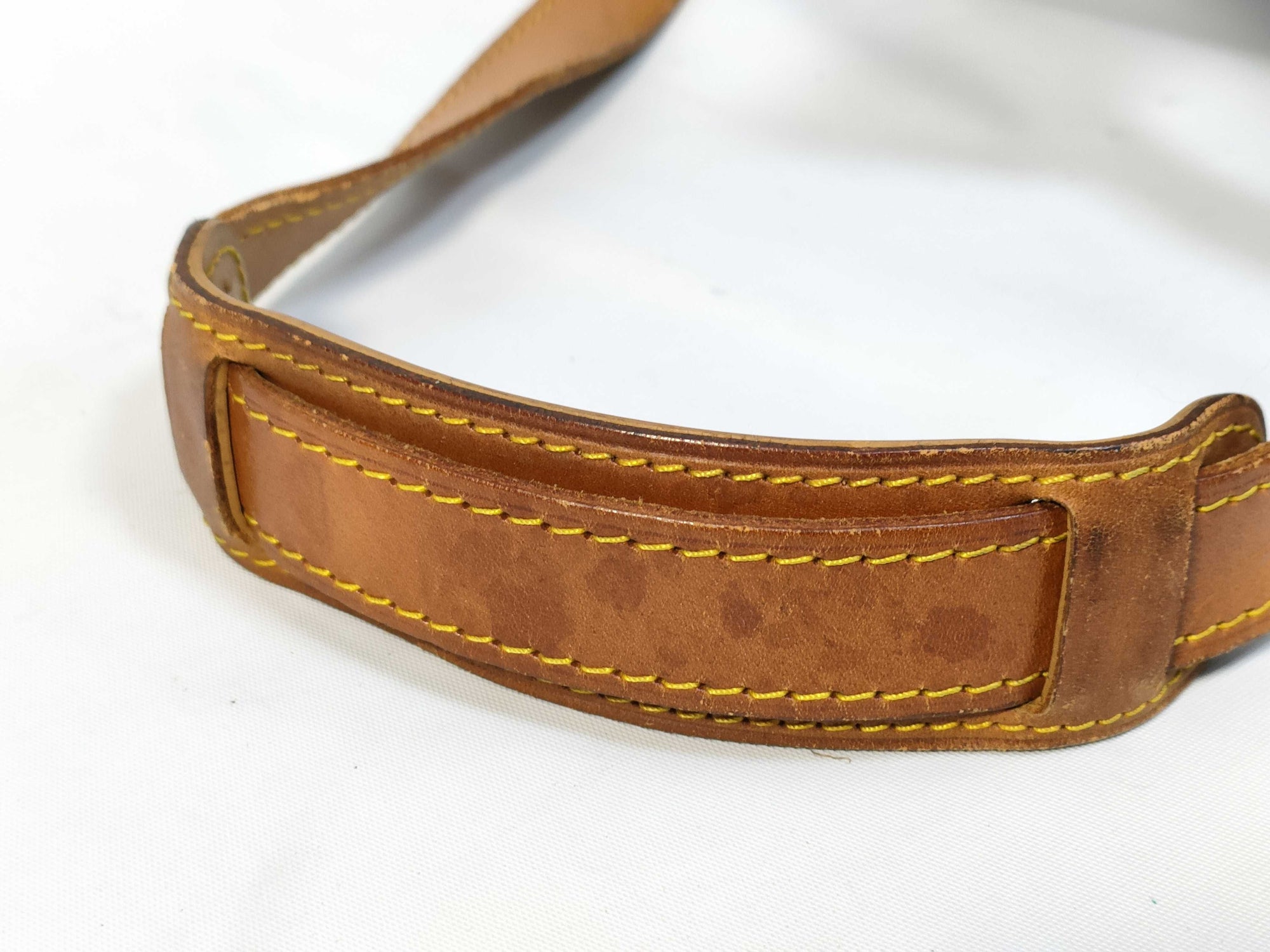 Vintage Louis Vuitton Keepall 55 Bandouliere leather shoulder strap with medium tanning and visible water stains.