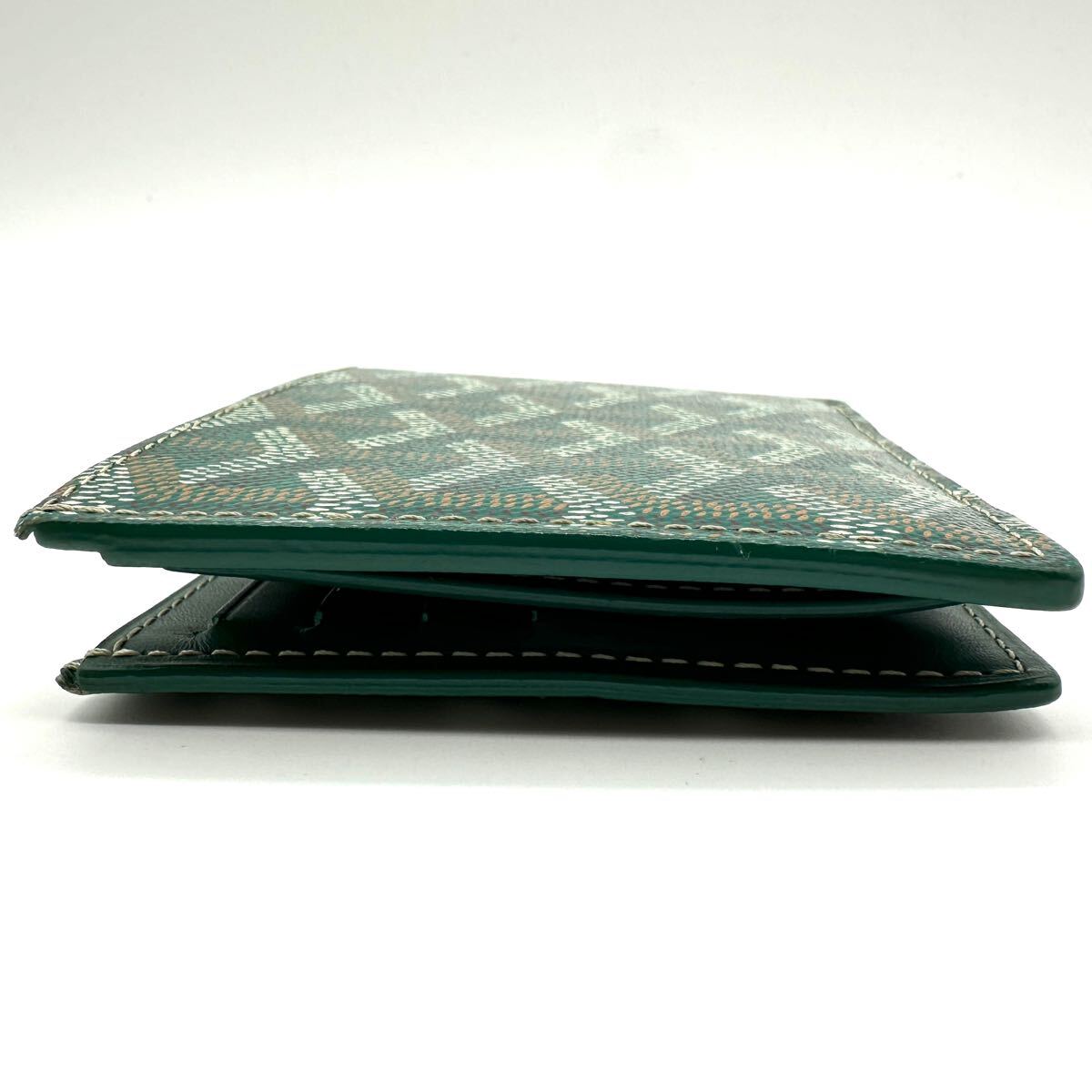 Side view of a green Goyard Saint Florentin bi-fold wallet in Goyardine canvas with white contrast stitching.