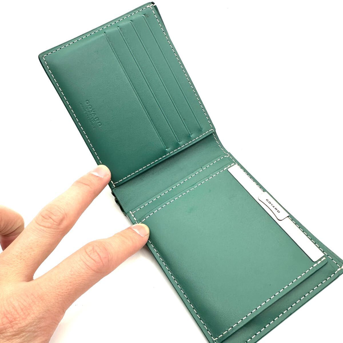 Open green Goyard Saint Florentin bi-fold wallet interior showing leather card slots and logo heat stamp.